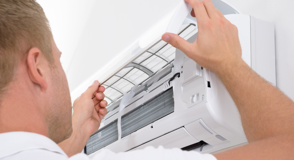 A person is adjusting the air conditioner 's filter.