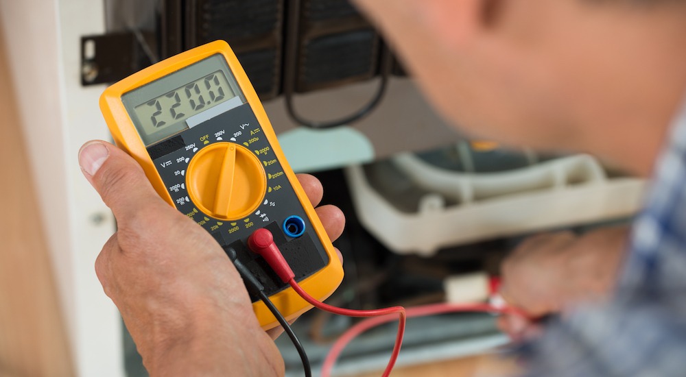 A man holding an electrical meter in his hand.