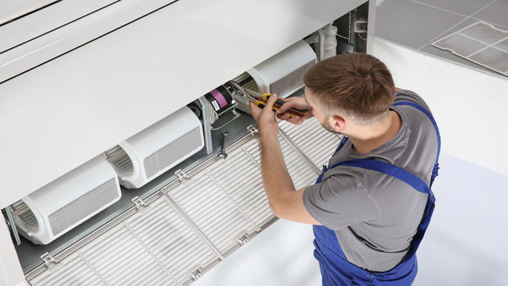 A man working on an air conditioner unit.