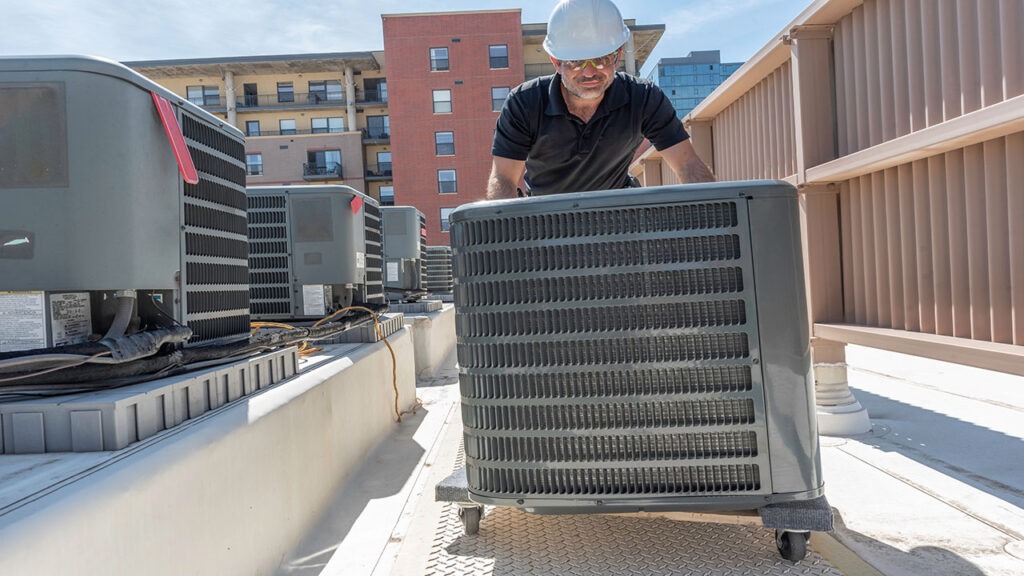 A man in black shirt pushing an air conditioner.