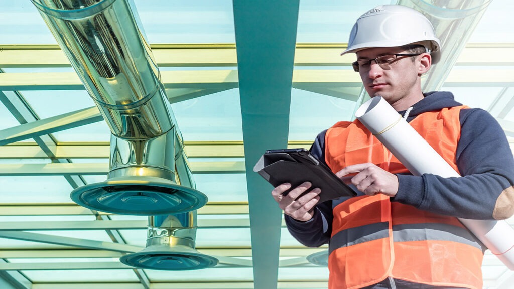 A man in an orange vest holding a tablet.