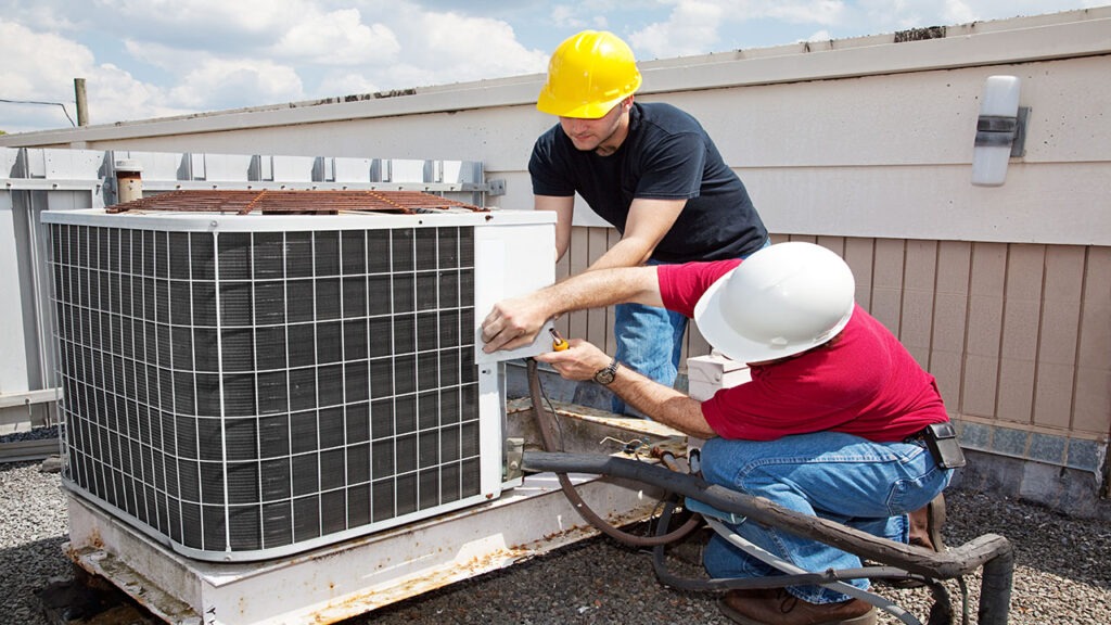 Two men working on a air conditioner unit.