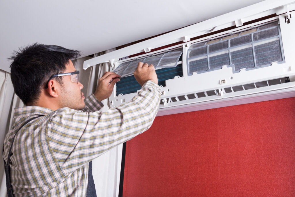 A man is fixing the air conditioner in his home.