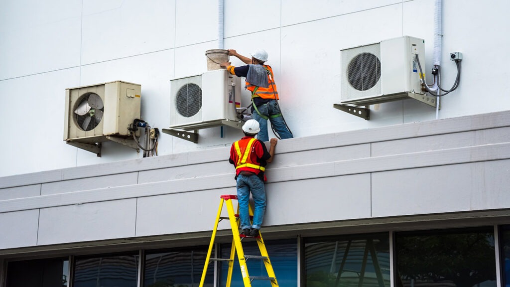 Two men working on a building with ladders.